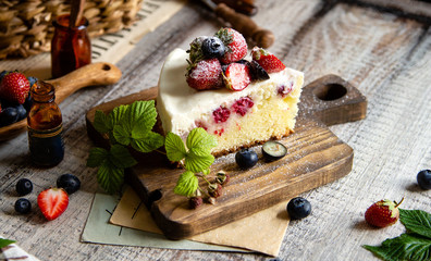 Naklejka na ściany i meble Homemade delicious slice of raspberry biscuit cake with white cream, strawberries, blueberries