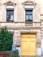 Germany Thuringen, vintage building facade with flower pots decorated windows and vibrant yellow door