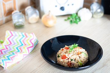 Bulgur salad with vegetables on the kitchen table with ingredients. Arabic couscous salad.