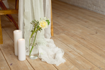 Branch of blooming white peony tulip Mattiola branch in a glass vase white wax candles stand on the wooden light floor indoors