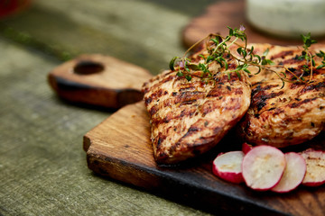 Grilled turkey meat. Steak turkey grill on wooden cutting board with a variety of grilled vegetables on  rustic background  Top view. Flat lay. Copy space..