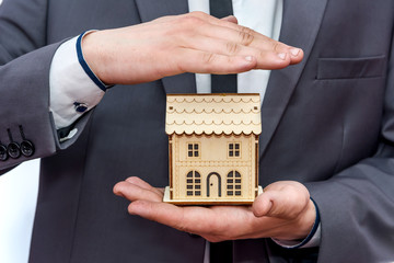 Male hands holding wooden house model close up