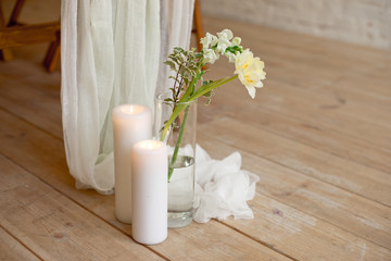 Branch of blooming white peony tulip Mattiola branch in a glass vase white wax candles stand on the wooden light floor indoors