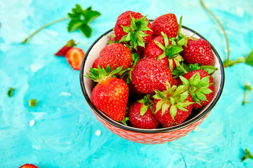 Ripe red strawberries on blue table, Strawberries in red bowl. Fresh strawberries. Beautiful strawberries. Diet food. Healthy, vegan. Top view. Flat lay.