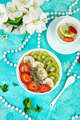 Healthy breakfast bowl smoothie with strawberry, banana, kiwi  and chia seeds on blue background. Healthy vegan food concept..