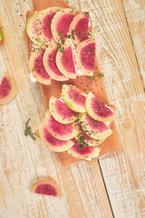 Healthy breakfast toasts from sliced watermelon radish or chinese daikon, chia and cottage cheese on board wooden background. Top view. Flat lay. Copy space.
