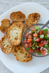 Preparing tasty tomato Italian appetizers -  bruschetta, on slices of toasted baguette, close up view.