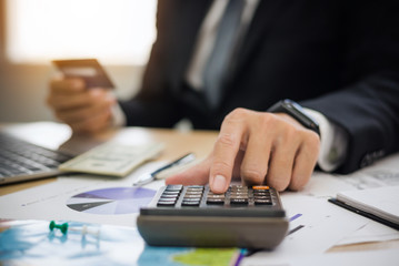 Businessman using calculator with credit card for shopping internet online ,Tourist planning vacation trip with Travel map booking hotel.