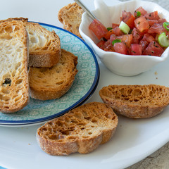 Preparing tasty tomato Italian appetizers -  bruschetta, on slices of toasted baguette, close up view.