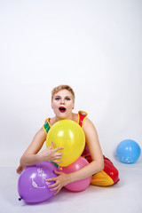 Fototapeta na wymiar funny happy clown girl with colorful air ballons on white studio background