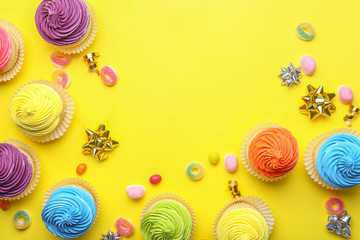 Sweet tasty cupcakes with candies on color background