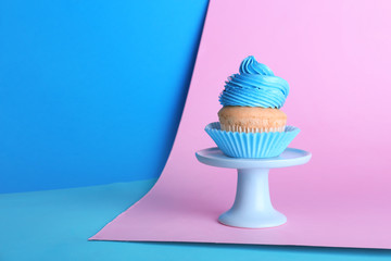 Stand with sweet tasty cupcake on color background