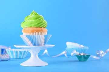 Stand with sweet tasty cupcake on color background