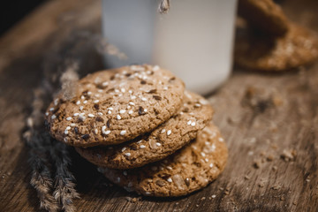 Cereal cookies with a jug of milk on a wooden background.
