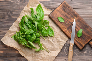 Board with fresh basil and knife on wooden table
