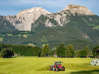 Traktor düngt ein Feld in den Alpen