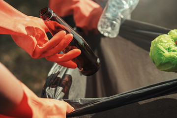 people hand holding garbage bottle plastic and glass putting into recycle bag for cleaning