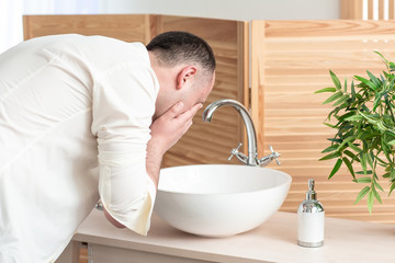 Man washing face in morning and practicing hygiene. The morning of the groom