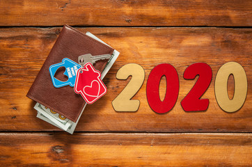 Key home and leather wallet on old wooden table. New year 2020