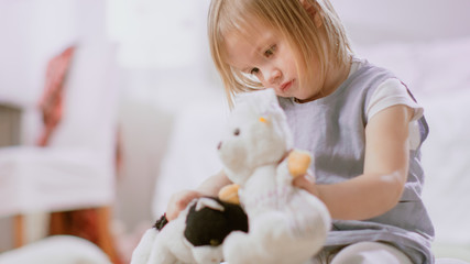 In the Childrens Room: Cute Happy Little Girl Playing with Doll House and Sitting on a Carpet. Sunny Living Room with Children Having Fun. 