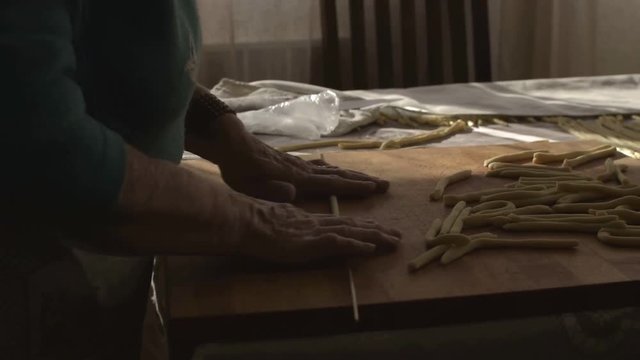 South Italian old woman rolling dough to prepare traditional Italian home made pasta.