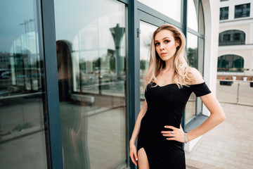 beautiful young girl in black dress walking the streets of the city, the woman is resting outdoors