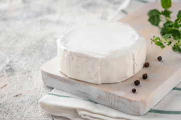 Wooden board with brie cheese. Italian antipasti snacks. French camembert cheese. Close-up.