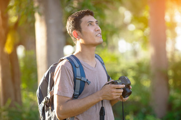 Young man photographer holding camera in forest 