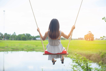 Asian woman on swing in countryside