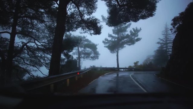 View of rainy foggy road with picturesque nature from driving car along roadside during journey. Cyprus. Slow motion.