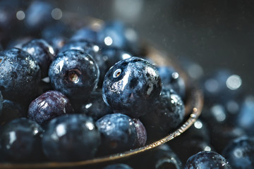 Juicy and fresh blueberries with green leaves on rustic table. Blueberry antioxidant. Concept for healthy eating and nutrition. Selective focus.