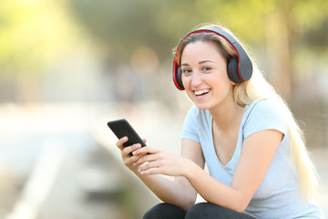 Happy teenage girl listening to music looking at camera