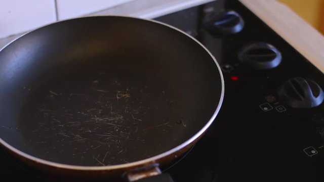 Man is putting frozen bacon in a frying pan