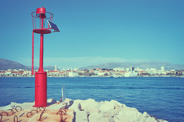 Little red metallic lighthouse on the shore of Split town harbour.