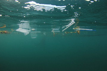 Fototapeta premium Plastic ocean. Pollution crisis as plastic bags, cups, straws and bottles end up in sea 