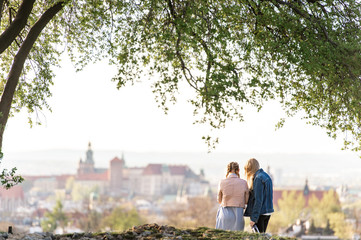 Female couple from behind on Krakus mound with a view at Wawel castle on background.