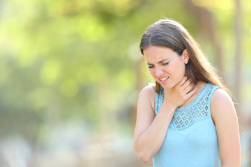 Woman suffering sore throat in a park