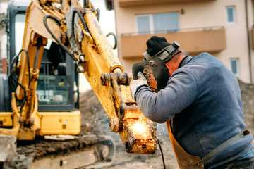Close up portrait of welder working on excavator on construction site, reparing and fixing - Powered by Adobe