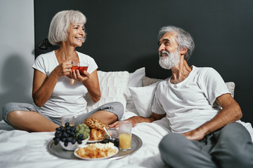 Good morning! Senior family couple enjoying breakfast in bed.