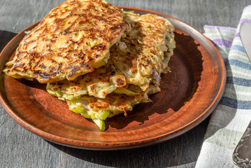 Vegetarian cuisine - Vegetable pancakes from cabbage and zucchini in a rustic clay plate on a wooden table