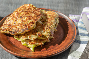 Vegetarian cuisine - Vegetable pancakes from cabbage and zucchini in a rustic clay plate on a wooden table