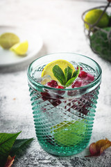 Glass with cranberry and lemon cocktail, close-up. Refreshing drink with ice.