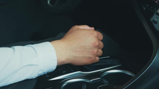 Close-up of male hands switching automatic gearbox in expensive car