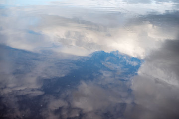 white clouds are reflected in the water