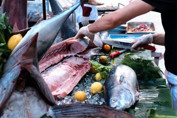 The restaurant chef cuts fish with a knife in the open air. Cooking swordfish. Fresh sea fish....