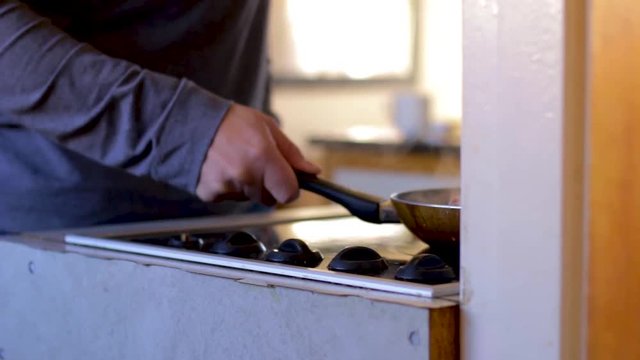 Man is busy cooking bacon in a frying pan