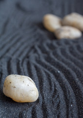 Top view of zen mini garden with dark sand with a stone in the foreground and stones in the background out of focus