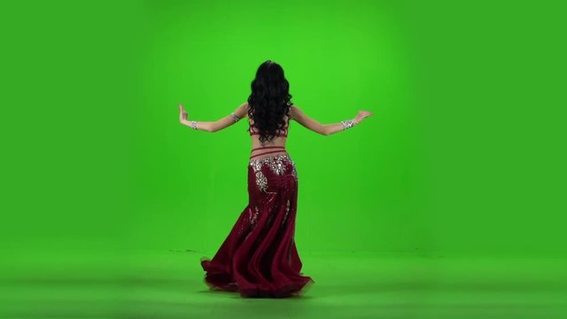 Girl performing belly dance. Green background. Slow motion