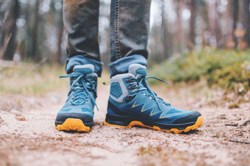 Male legs wearing sportive hiking shoes outdoor. Mens legs in trekking boots for outdoor activity