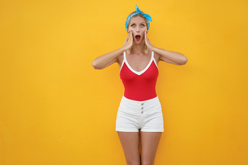 Wow! Shock! Expressing joy! Happy pretty young woman in shorts. Yellow wall background.